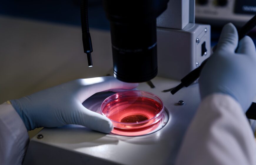 Closeup shot of a person studying coronavirus particles with a microscope