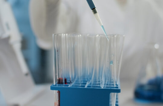 Specialist working with micro pipette to drop liquid in beaker