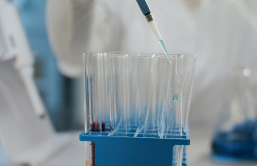 Specialist working with micro pipette to drop liquid in beaker